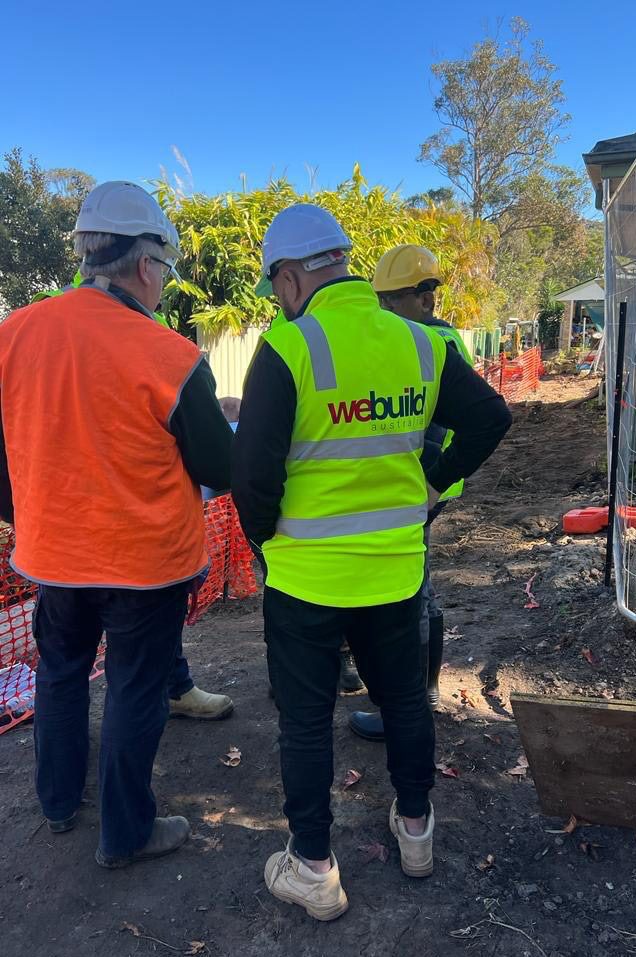 We Build Australia team member in branded vest on site — representative of live-environment construction coordination