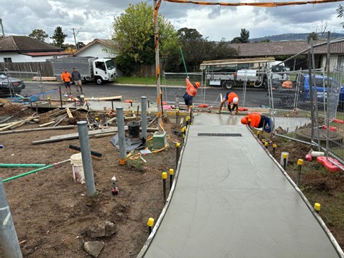Kelso — Culnane Place: newly poured concrete pathway under construction with safety fencing, bollards and accessibility-compliant edging