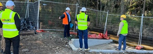 Kincumber — We Build Australia site team in branded high-vis discussing newly poured concrete drainage works