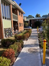 Marks Point — refreshed accessible pathway between LAHC residential blocks with garden bed and safety bollard