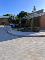 Marks Point — completed brick-paver driveway with new landscaping and concrete kerb at single-storey LAHC residential complex