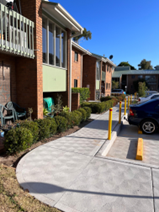Marks Point — new accessibility-compliant pathway with safety bollards and concrete edging between residential blocks