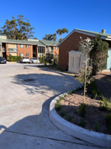Marks Point — new brick paver driveway with garden bed planting and concrete kerb between residential blocks