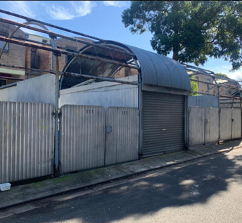 Walker Street, Waterloo — BEFORE: dilapidated waste-room enclosure with sheet-metal gates and curved tin awning prior to rebuild